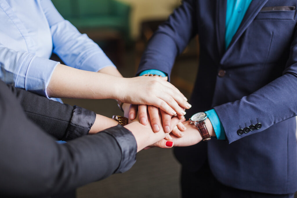 people-standing-office-holding-hands-together